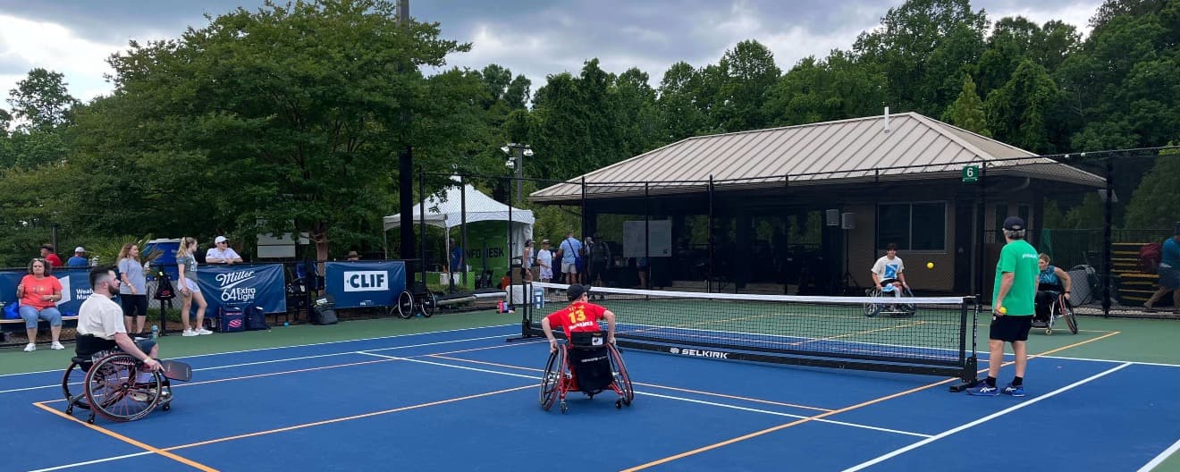 Four people playing pickleball in wheelchairs