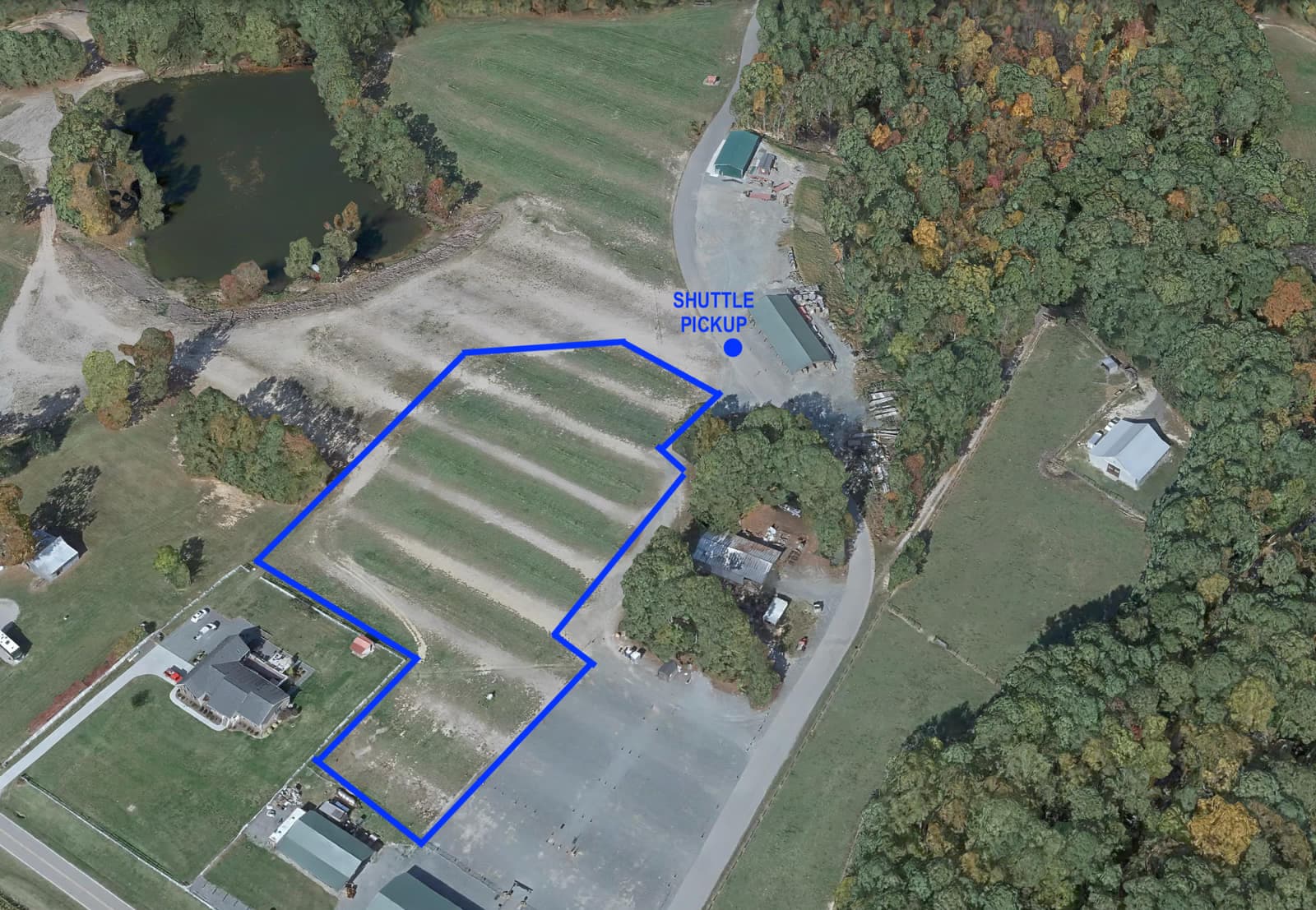 Aerial map of the Phillips Farms parking lot in Cary, NC, with the free grass parking area outlined in blue and the shuttle pickup point marked at its northeast corner.