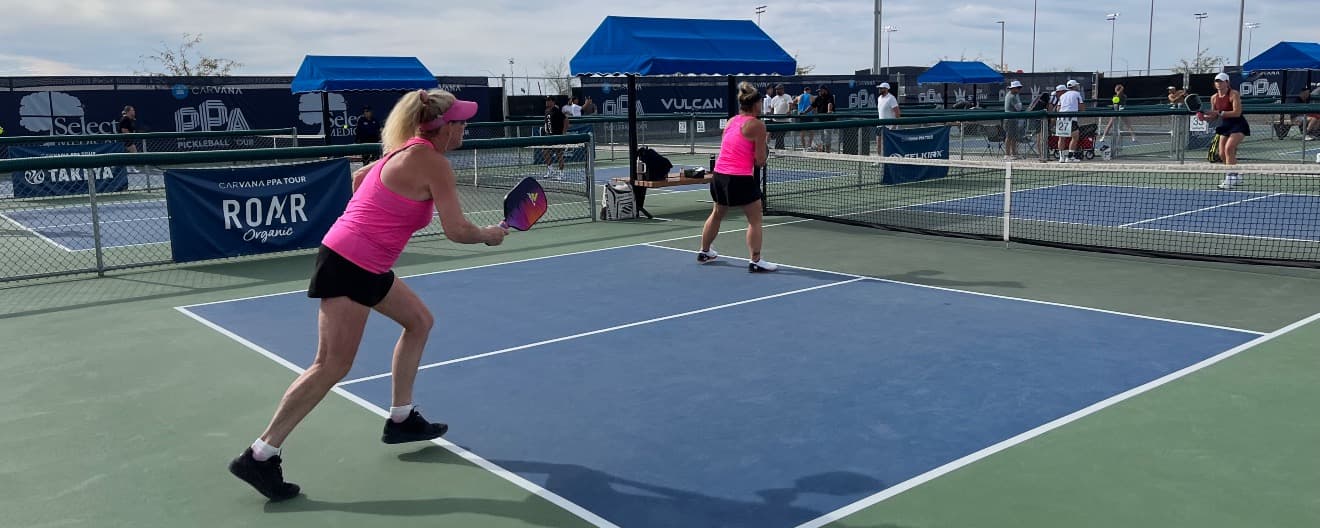 Amateur pickleball players wear bright pink shirts and visors on the pickleball court at Mesa Arizona Cup