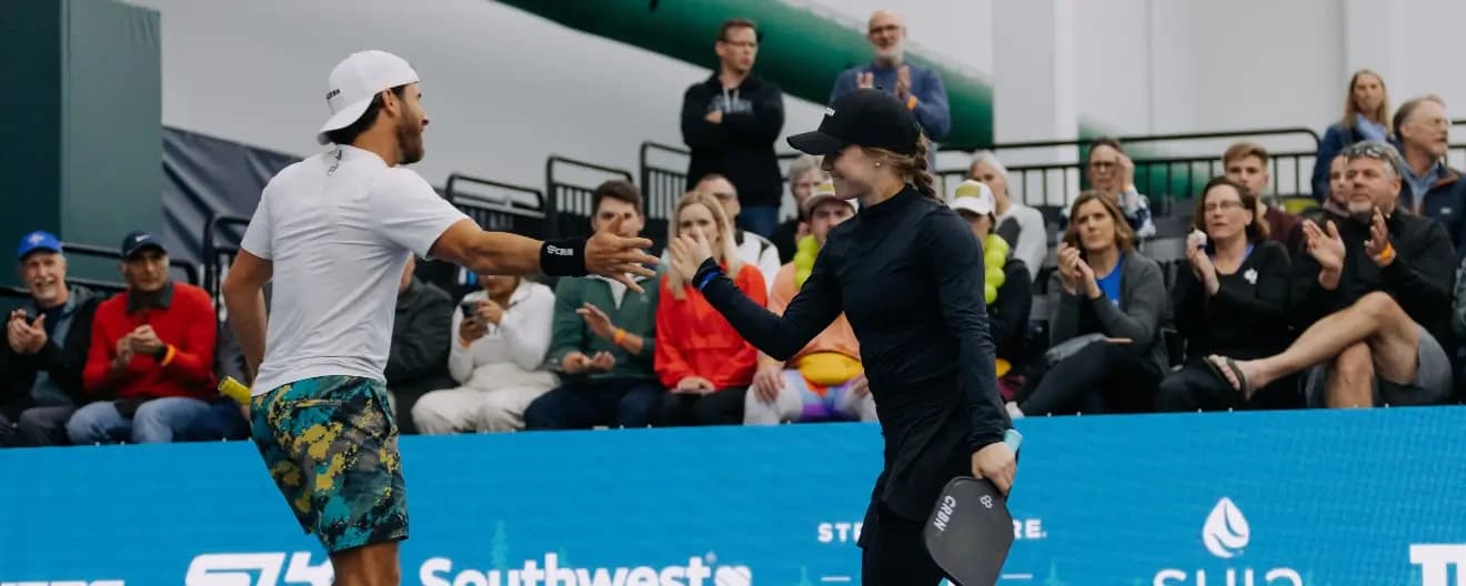 Thomas Wilson and Vivienne David giving each other a high five playing pickleball.