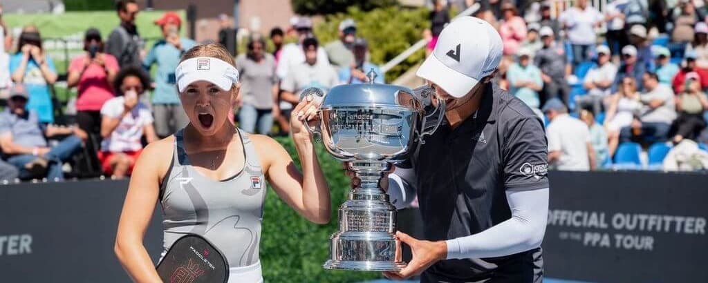 Ben Johns biting the trophy and Anna Leigh Waters' mouth agape