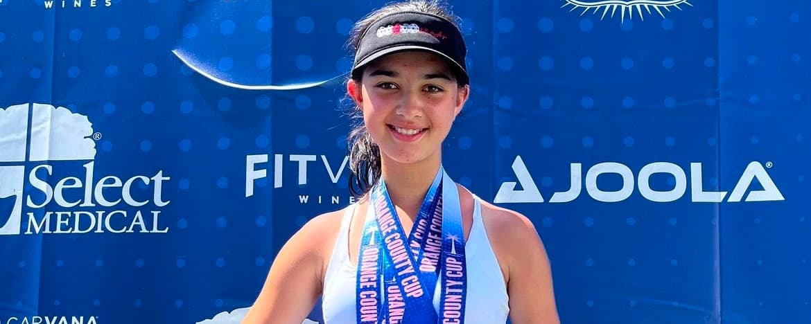 Ella Cosma standing on a podium with three gold medals around her neck