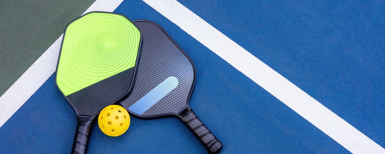 Two pickleball paddles on a pickleball court.