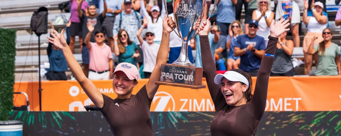 Anna Bright and Rachel Rohrabacher holding their trophy up in the air in victory after their win.