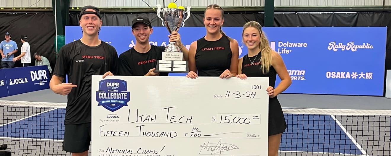 Four Utah Tech players holding up a trophy and big check.