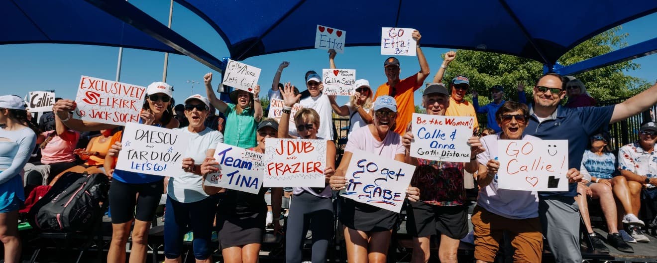 Group of fans holding up signs for pro pickleball players.